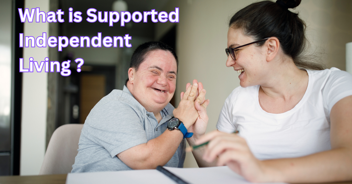 A person with a disability and a woman are happily interacting at a table. The text "What is Supported Independent Living?" is displayed at the top.